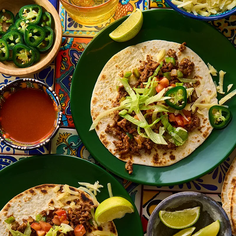 Spicy Minced Beef Tacos Recipe Spicy minced beef tacos served with lettuce, green chilli, tomatoes and spices in small wooden tray