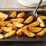 Roasted potato wedges on a baking tray with a spatula