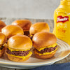 A platter of juicy beef sliders topped with melted cheese and Frenchs Classic Yellow Mustard is presented alongside a bottle of the Global Visionary Template Uk.