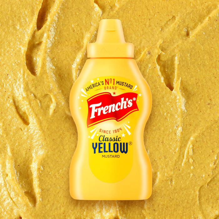 A bottle of Frenchs Classic Yellow Mustard belonging to the Global Visionary Template Uk is centered against a textured background of spread yellow mustard.