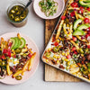 A delicious tray of loaded fries is topped with a savory chili made using Schwartz Hot Chilli Con Carne Recipe Mix 41G, alongside fresh avocado, jalapeños, and corn.