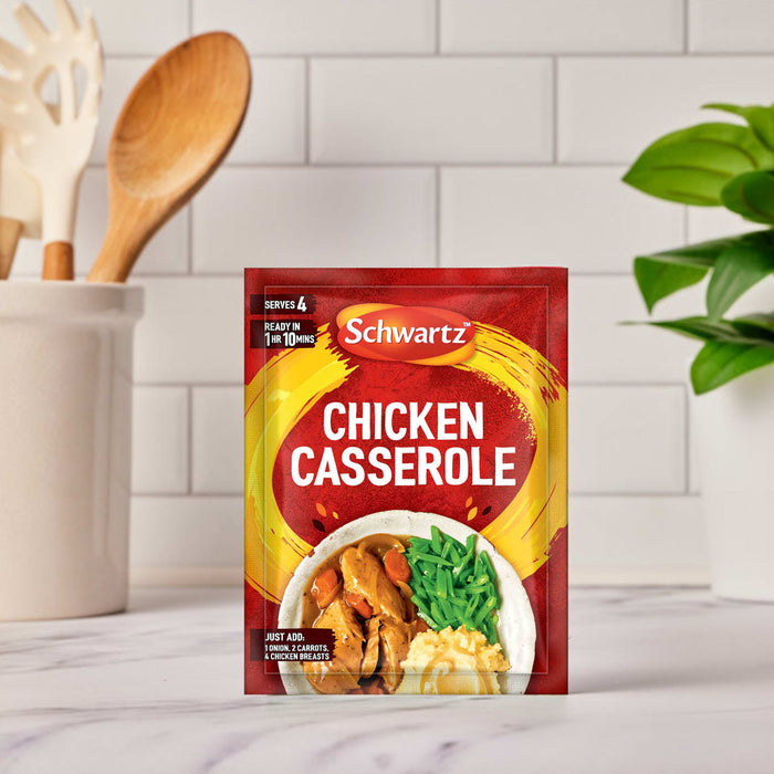 A packet of Schwartz Chicken Casserole Recipe Mix 36G is shown on a kitchen countertop, with cooking utensils visible in the background.