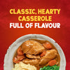 A close-up of a rustic bowl filled with a hearty chicken casserole, made using Schwartz Chicken Casserole Recipe Mix 36G, served with mashed potatoes and green beans against a red background.