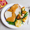 A plate of sliced pork with gravy, roasted potatoes, and green beans is shown next to a packet of Schwartz Somerset Pork Casserole Recipe Mix 36G, suggesting a delicious meal idea.