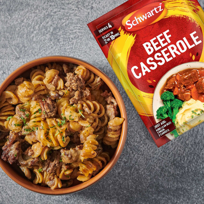 A brown bowl filled with a creamy beef and fusilli pasta dish is presented alongside a packet of Schwartz Beef Casserole Recipe Mix 38G against a grey, textured background.