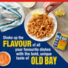 A hand reaches for a piece of crispy fried calamari seasoned with Old Bay on a plate with lemon wedges and dipping sauces.