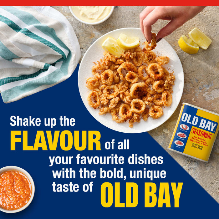 A hand reaches for a piece of crispy fried calamari seasoned with Old Bay on a plate with lemon wedges and dipping sauces.
