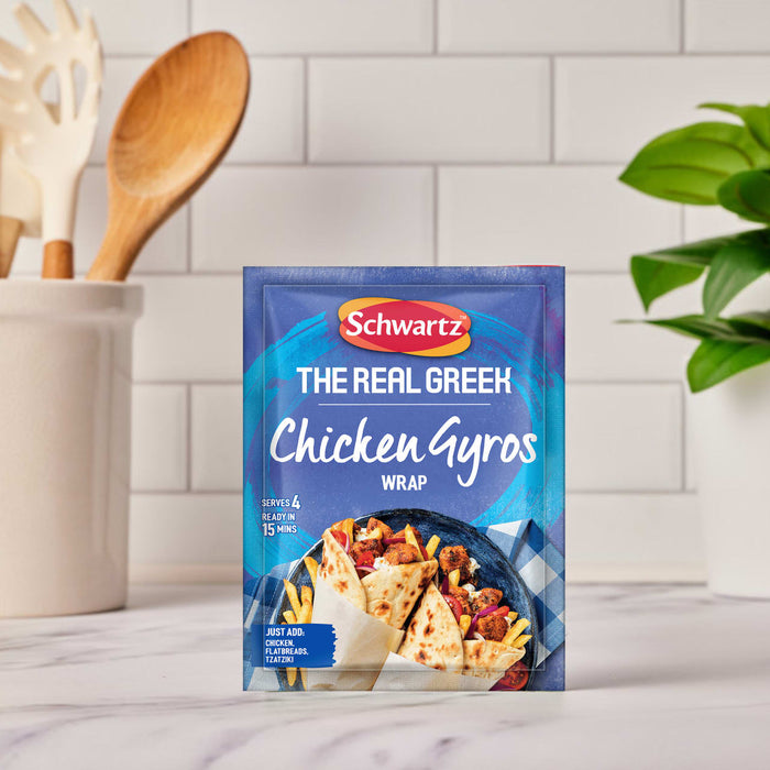A packet of Schwartz The Real Greek Chicken Gyros Wrap 20G is set on a white marble countertop in a kitchen setting.