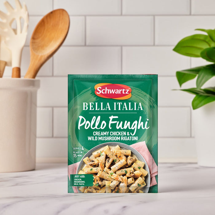 A green sachet of Schwartz Bella Italia Pollo Funghi Creamy Chicken & Wild Mushroom Rigatoni 30G is centered on a kitchen countertop, with a utensil holder and a small plant in the background.