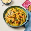 A vibrant bowl of chicken curry over yellow rice is shown as a serving suggestion, with the pink packet of Schwartz Las Iguanas Bahian Coconut Curry 25G visible in the corner.
