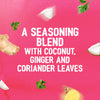 A vibrant pink background with floating ingredients like coconut, ginger, and coriander leaves highlights the flavor profile of the Schwartz Las Iguanas Bahian Coconut Curry 25G, described as a seasoning blend.