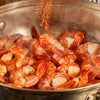 A generous amount of Schwartz Smoked Paprika 40G is sprinkled over steaming shrimp as they cook in a large metal pan.