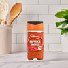 A jar of Schwartz Smoked Paprika 40G sits on a white marble kitchen counter, with cooking utensils and a white tiled wall in the background.