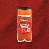 A clear jar of Schwartz Smoked Paprika 40G is centered in a product shot, resting on a bed of the same vibrant red spice to showcase its color and texture.