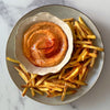 A plate of golden french fries is served with a creamy, swirled dipping sauce that has been garnished with a sprinkle of Schwartz Smoked Paprika 40G.