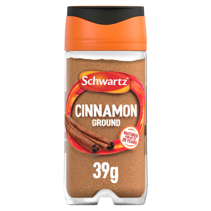 A clear glass jar of Schwartz Ground Cinnamon 39G is shown against a white background, featuring an orange and black cap and a label with an image of cinnamon sticks.