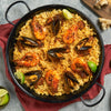 A large pan of delicious seafood paella with prawns and mussels gets its aromatic flavor from Schwartz Cumin Ground 37G, served with fresh lime wedges.