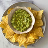 A rustic bowl of freshly made guacamole, perfectly seasoned with Schwartz Garlic Granules 50G, is presented on a platter surrounded by tortilla chips.