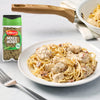 A bottle of Schwartz Mixed Herbs 11G stands next to a plate of creamy chicken and bacon pasta garnished with the herb blend.