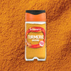 A clear jar of Schwartz Turmeric Ground 37G sits centered on a bed of the vibrant, golden-orange spice.