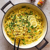 A large pot of vibrant yellow spaghetti with peas and lemon is shown as a delicious meal idea using Schwartz Turmeric Ground 37G, with the spice jar visible in the background.