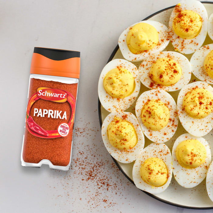 A jar of Schwartz Paprika 40G is placed next to a plate of deviled eggs that have been garnished with the spice.