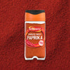 A clear jar of Schwartz Smoked Sweet Paprika 40G is centered on a background of the same vibrant red spice.