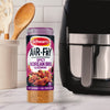 A container of Schwartz Af Sy Korean Seas stands on a marble countertop next to a black air fryer and kitchen utensils.