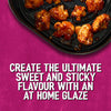 A top down view of cauliflower florets coated in a sweet and sticky glaze made with Schwartz Af Chinese Cs Sea in an air fryer basket against a pink background.