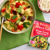 A finished bowl of Thai green curry with chicken and vegetables is displayed next to a bowl of rice and the Schwartz Sa Rt Green Curry X12 packet used to prepare the meal.