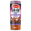 A cylindrical container of Schwartz Air Fry Smoky Tandoori BBQ Seasoning features a label with a bowl of cooked chicken and clear plastic at the bottom revealing reddish orange spice powder.