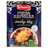 A packet of Schwartz Pizza Express Smoky BBQ Chicken Bake seasoning mix is shown in front of a serving suggestion of a cheesy chicken breast on a bed of roasted vegetables and salad greens.