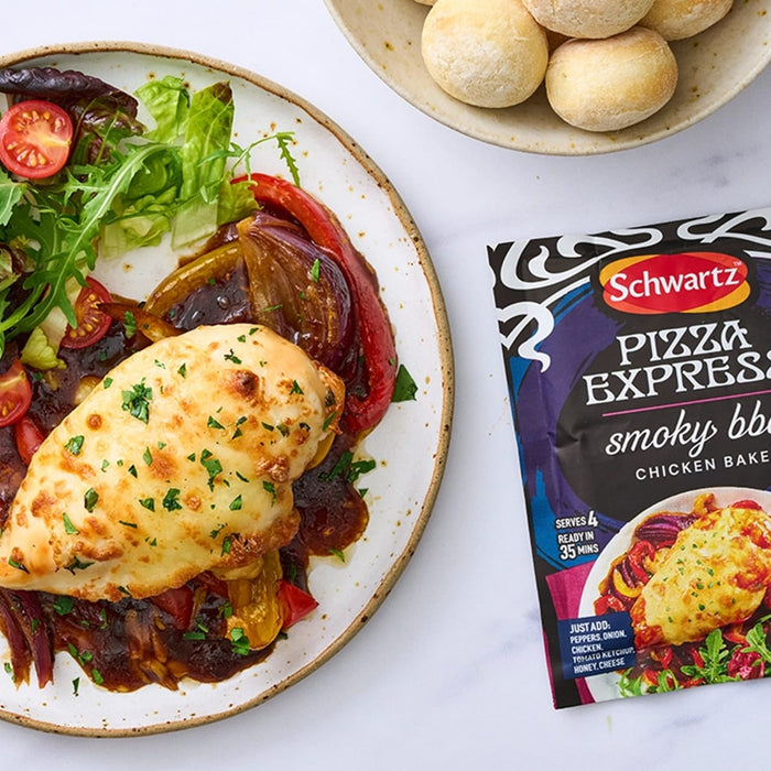 A creamy pasta bake with spinach and dollops of ricotta cheese is presented in a white skillet alongside a packet of Sa Pe Smoky Bbq Chickbake X12 by Schwartz.