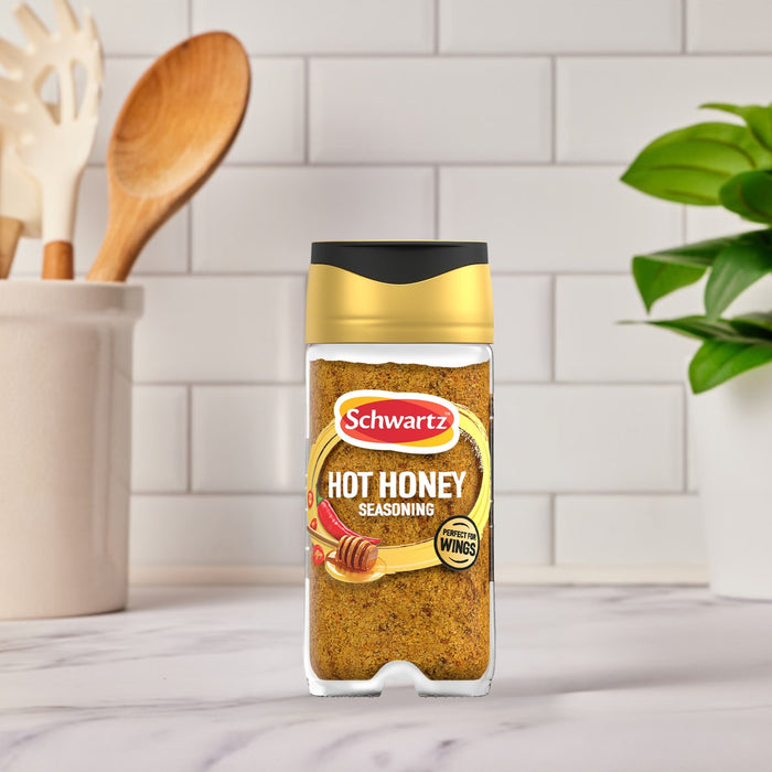 A bottle of Schwartz Jr Hot Honey Seas X6 stands on a marble countertop in a bright kitchen setting.