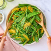 A vibrant green bean and snow pea salad is tossed with orange segments and a sprinkle of Jr Every Bagel Seas X6 for added texture and flavor.