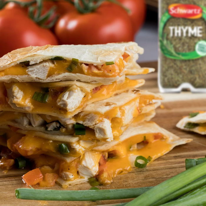 A delicious stack of cheesy chicken quesadillas is presented on a wooden board, with a package of Schwartz Thyme 11 G visible in the background.