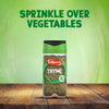 A jar of Schwartz Thyme 11 G sits on a wooden table, with the words SPRINKLE OVER VEGETABLES in the green background.