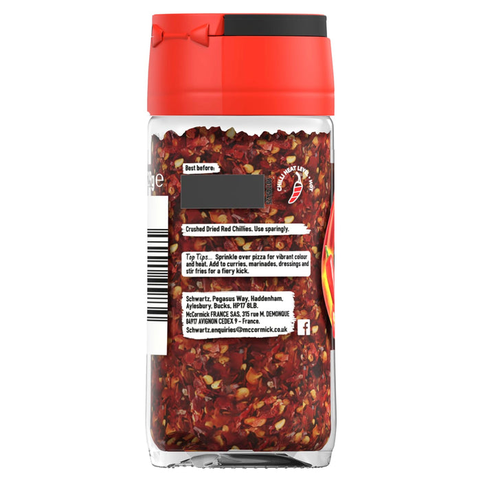 The back of a clear glass jar of Schwartz Crushed Chillies 29G displays the label with usage tips, company information, and a chilli heat level indicator.