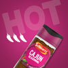 A bottle of Schwartz Cajun Seasoning 44G is displayed at an angle against a vibrant magenta background featuring the word HOT and three chili pepper icons.