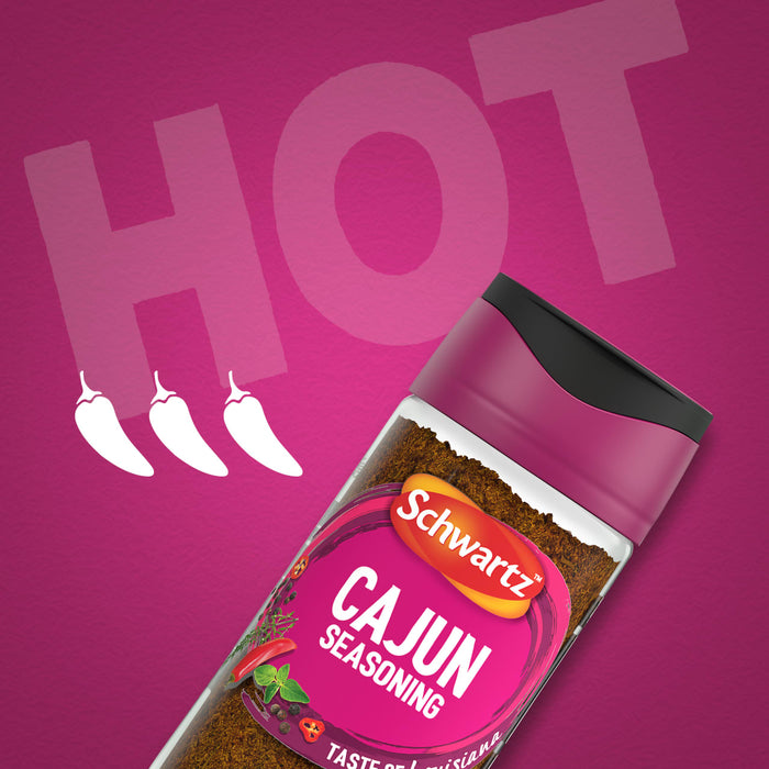 A bottle of Schwartz Cajun Seasoning 44G is displayed at an angle against a vibrant magenta background featuring the word HOT and three chili pepper icons.