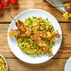 Grilled chicken and pineapple skewers seasoned with Schwartz Cajun Seasoning 44G are served over a vibrant bed of vegetable rice on a white plate.