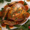 A beautifully roasted holiday turkey is presented on a platter with orange slices and generously sprinkled with Schwartz Parsley, 3G for a flavorful and festive finish.