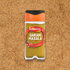 A clear jar of Schwartz Garam Masala, 30G, is shown from above, resting on a bed of the same ground spice blend.