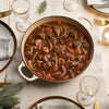 A hearty beef stew, made with a rich seasoning blend from the Barrel collection, is served in a large pot on a festively decorated dinner table.