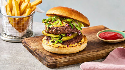 Hamburger with fries and ketchup on a wooden board