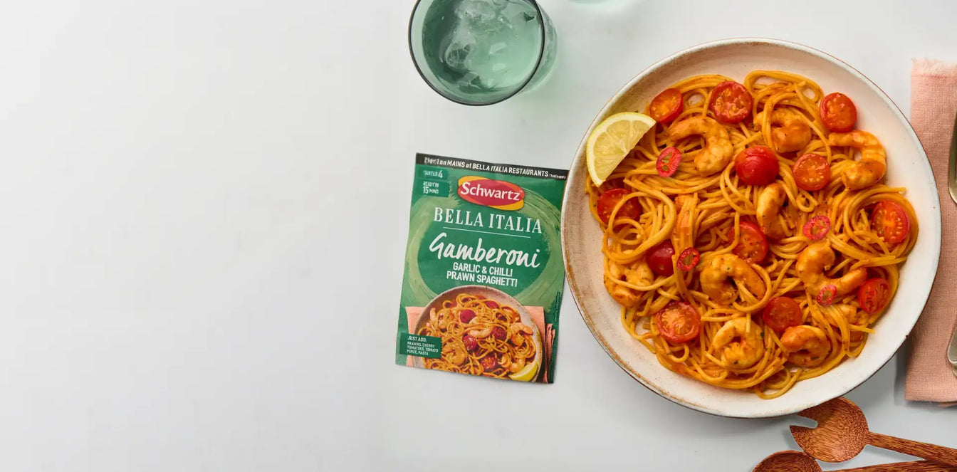 Plate of spaghetti with cherry tomatoes and a package of Schwartz Bella Italia Gamberoni on a white surface.