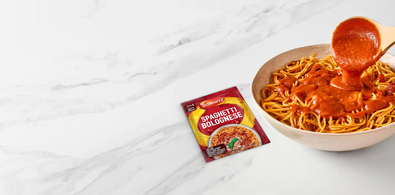 Spaghetti Bolognese packaging with a bowl of spaghetti being topped with sauce on a marble surface