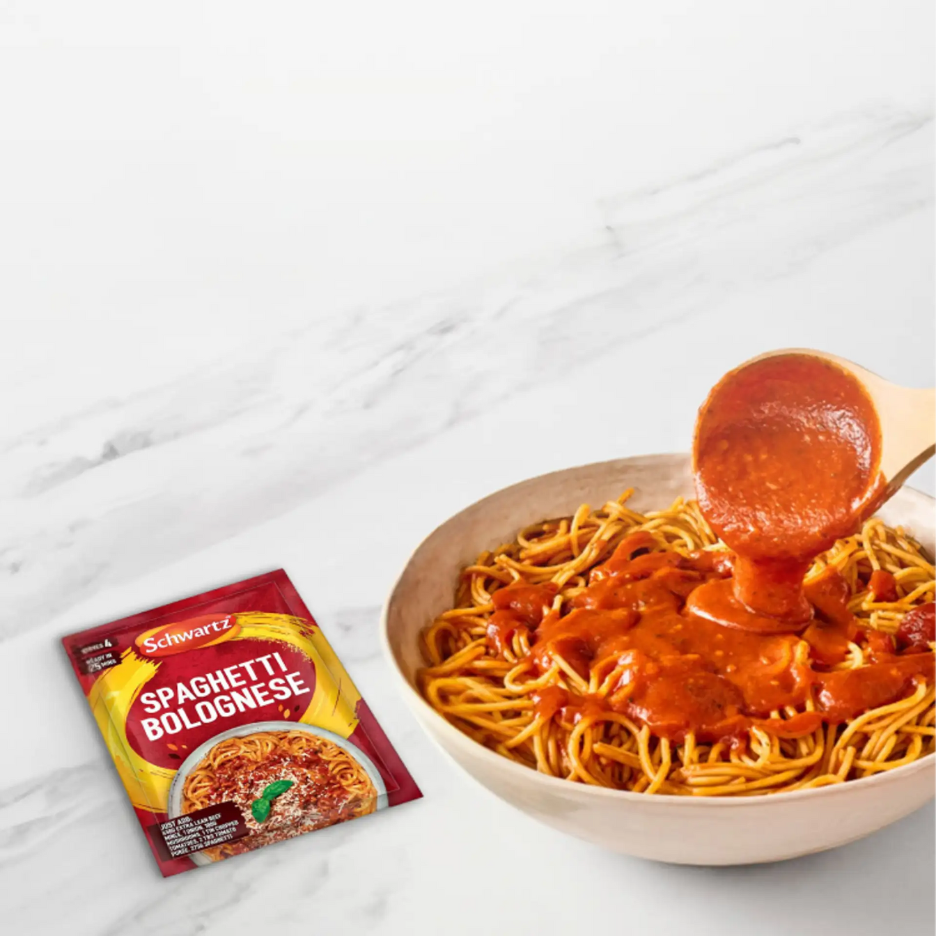 Spaghetti Bolognese packaging with a bowl of spaghetti being topped with sauce on a marble surface