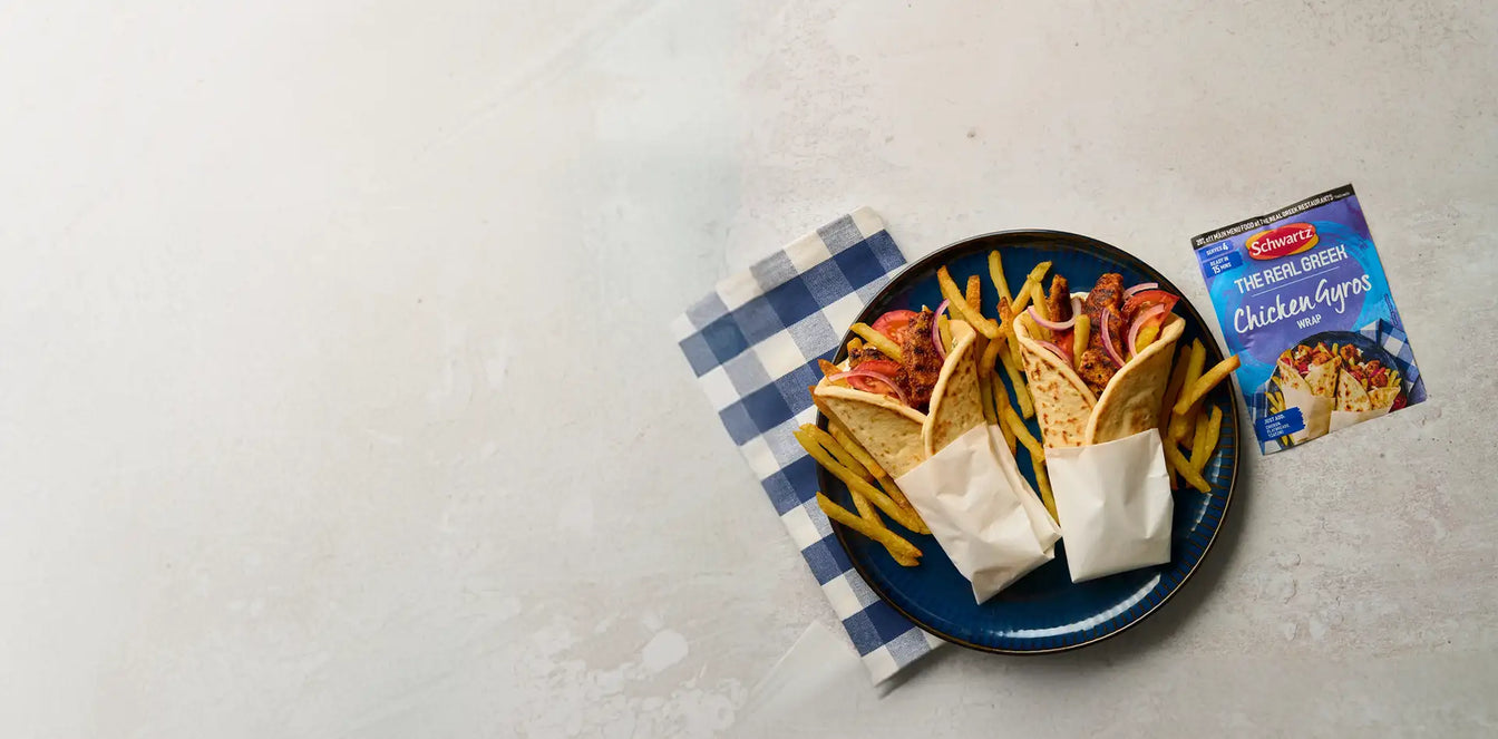 Two chicken gyros with fries on a blue plate next to a package of Schwartz's Chicken Gyros.