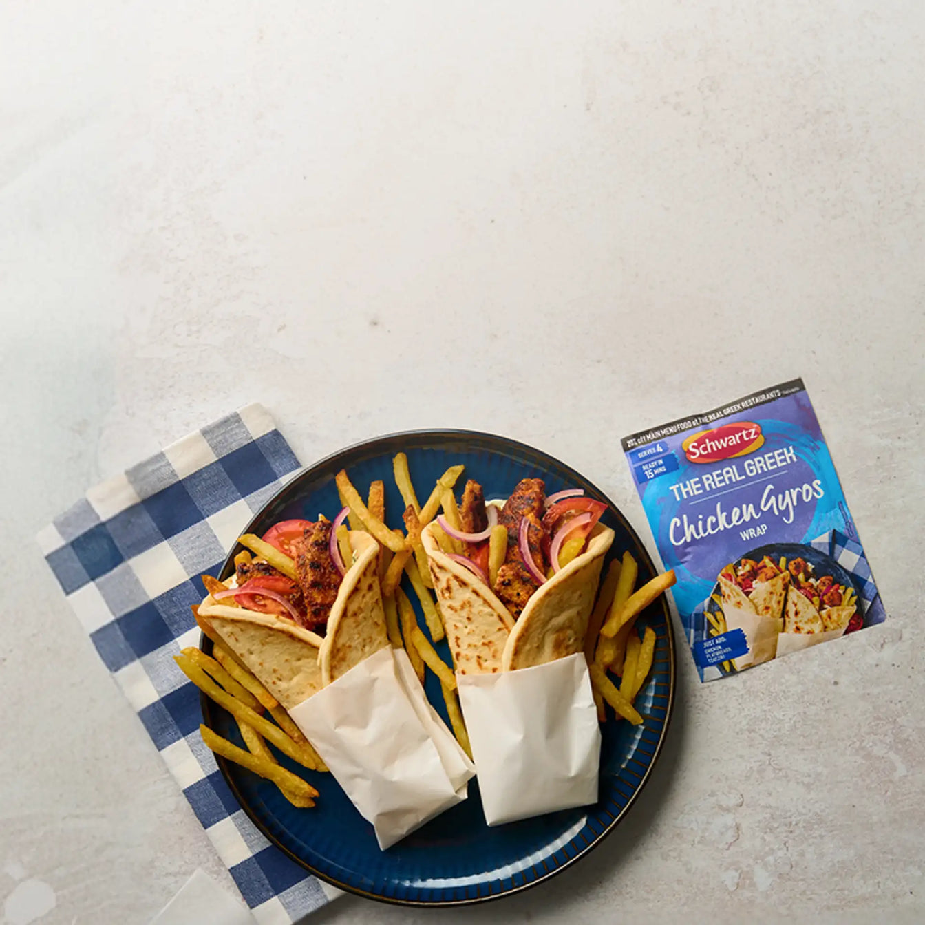 Two chicken gyros with fries on a blue plate next to a package of Schwartz's Chicken Gyros.